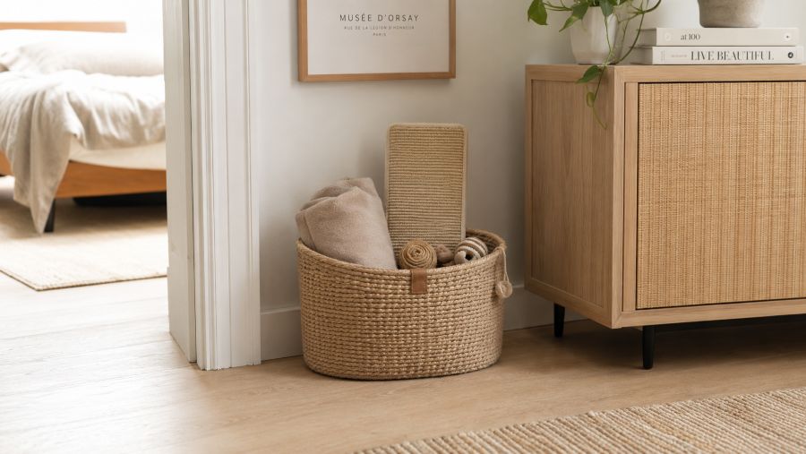 Neutral-toned cat supplies and toys organized in a single basket in a tidy apartment