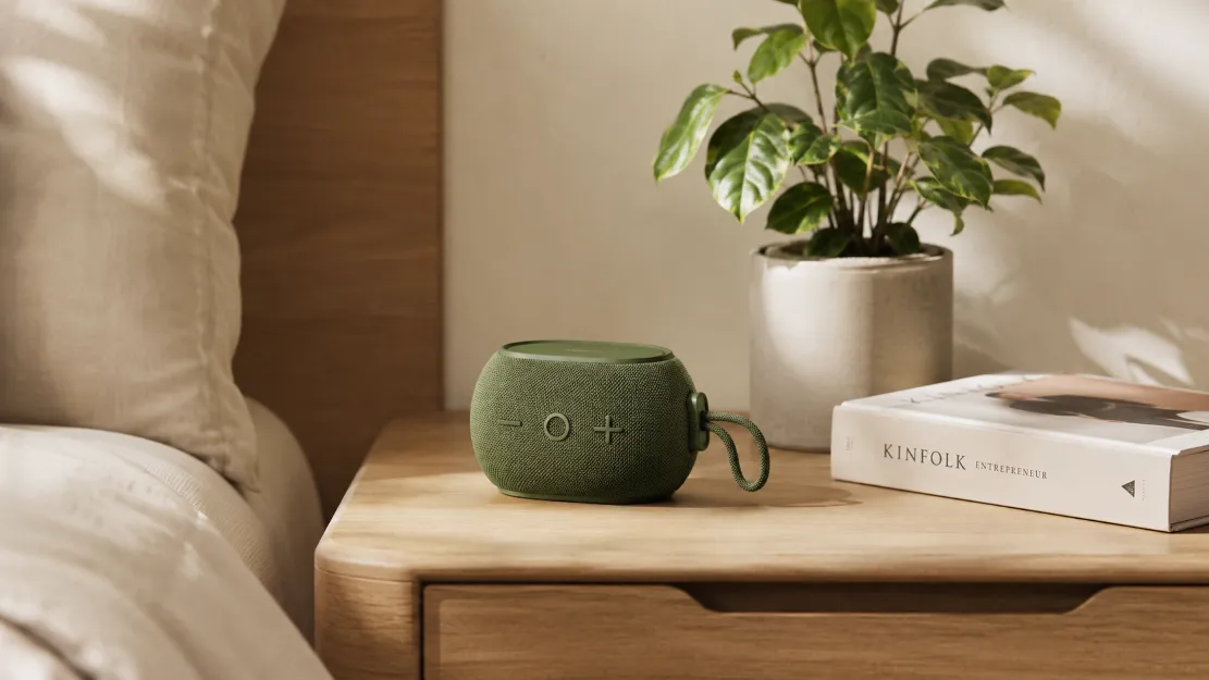 Portable compact Bluetooth speaker on a tidy bedside table in a cozy room