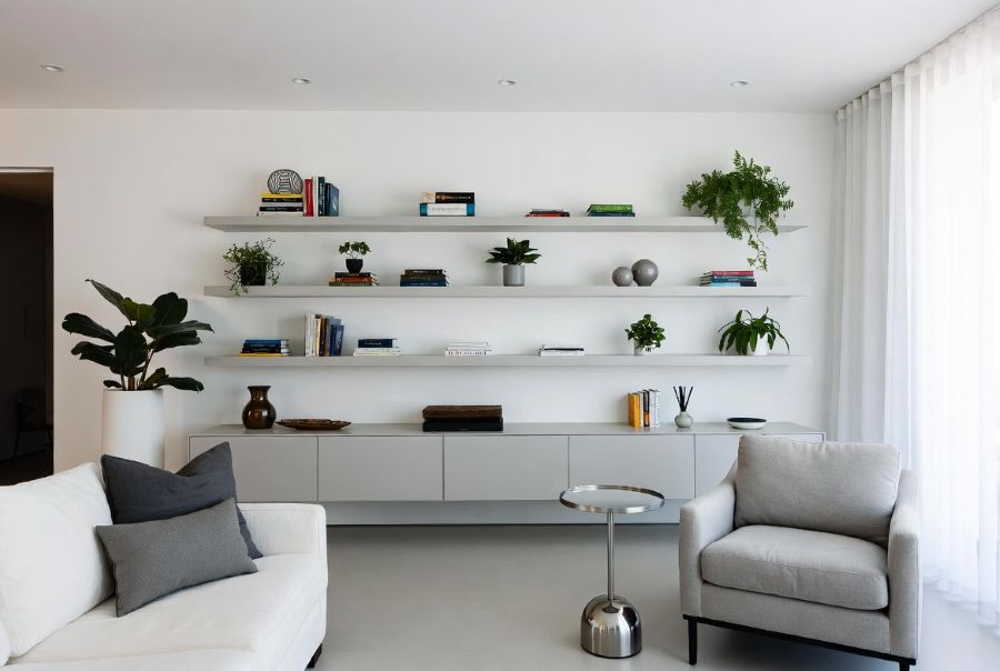 Wall-mounted floating shelves in minimalist small apartment living room with styled storage and decorative items